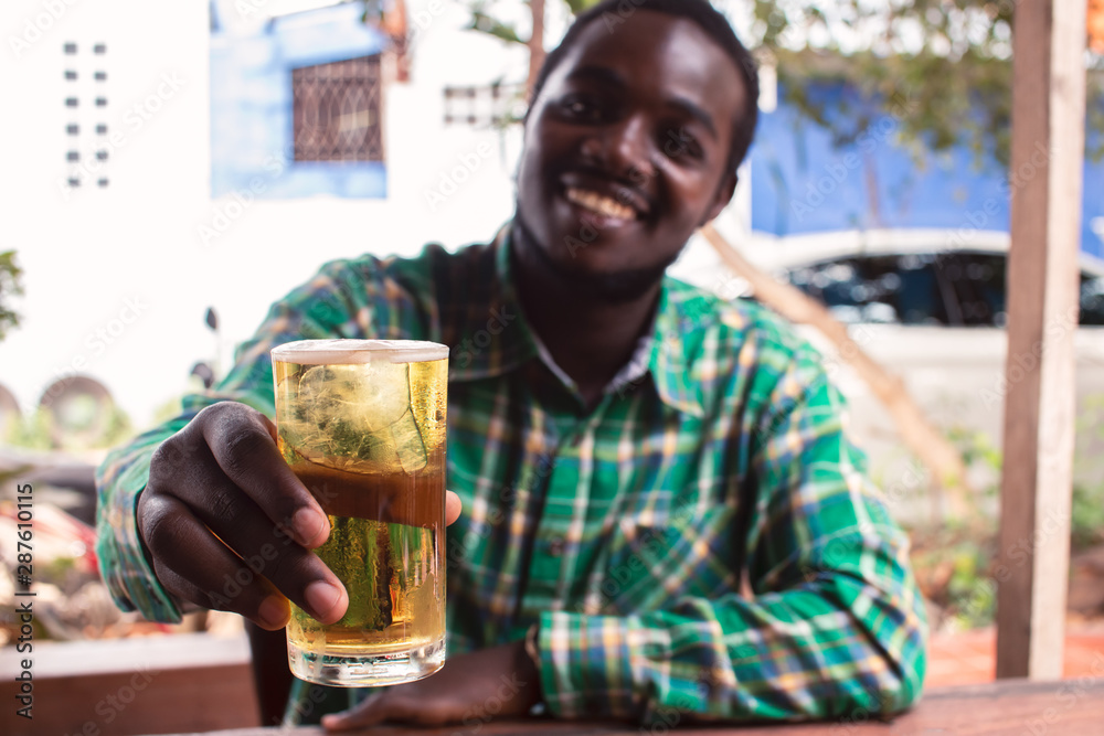 African man  smiling and holding a glass of beer