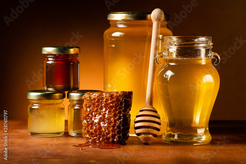 Various types of honey in glass jars with ladle and honeycomb. Still life photo