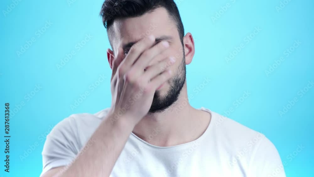 displeased man covering face on blue displeased man covering face on blue