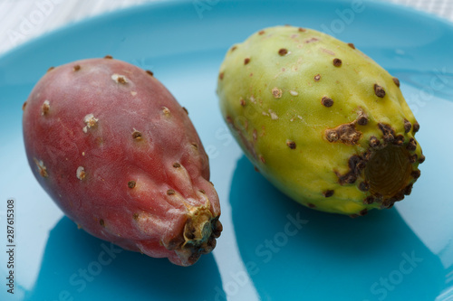 Close up view of pair of red a yellow indian figs (also called prickly pear) on a blue plate