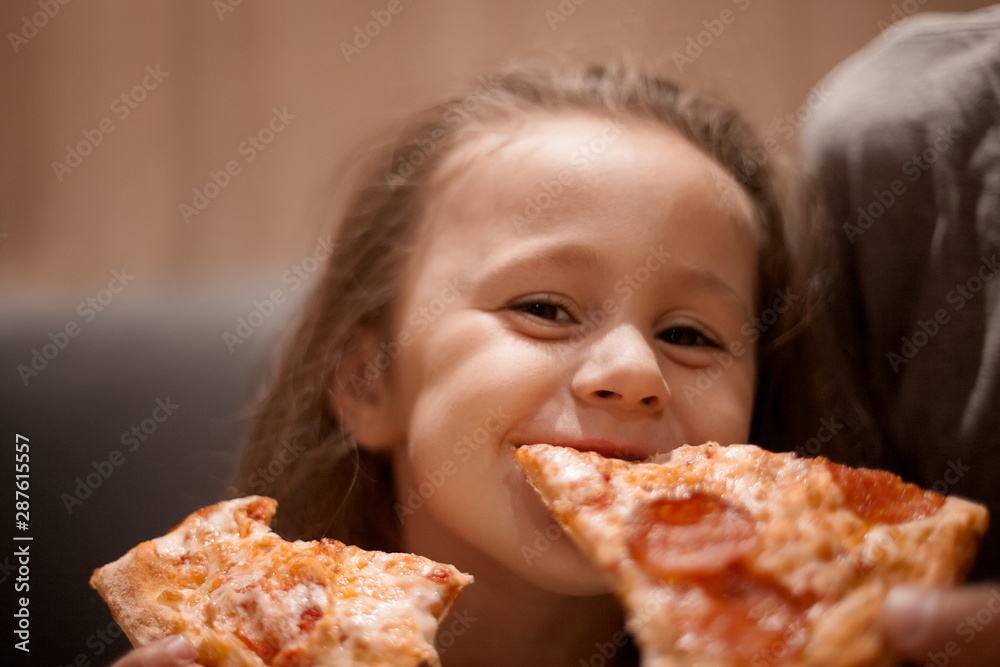 father feeding his cute daughter with pizza