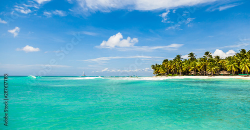 Fototapeta Naklejka Na Ścianę i Meble -  Beautiful tropical beach with white sand, coconut trees and turquoise sea water of the Caribbean on an island in the Dominican Republic. Paradise island for travel and recreation. Panorama copy space