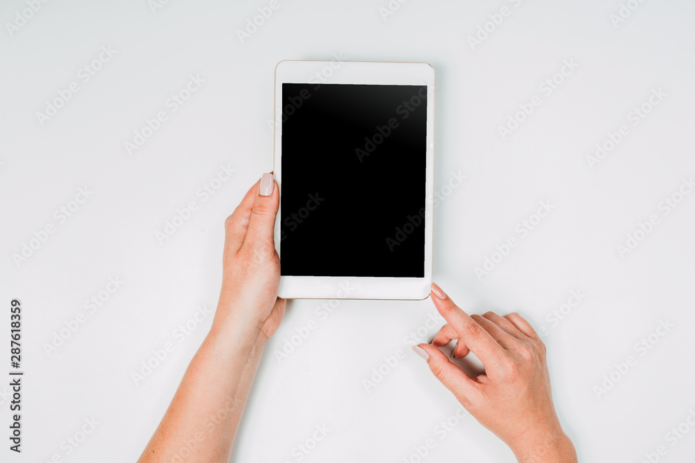 Modern workspace with woman hands and tablet pc copy space on white color background. Top view. Flat lay style. Minimalism