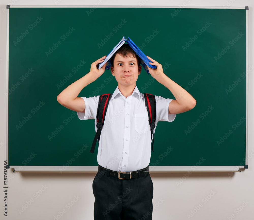Portrait of a school boy posing with backpack and school supplies, blackboard background - back to school and education concept Portrait of a school boy posing with backpack and school supplies, blackboard background - back to school and education concept