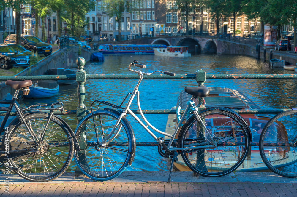 Amsterdam, North Holland / Netherlands - June 22nd, 2019: Bicycles parked along a bridge over the canals Amsterdam, North Holland / Netherlands - June 22nd, 2019: Bicycles parked along a bridge over the canals