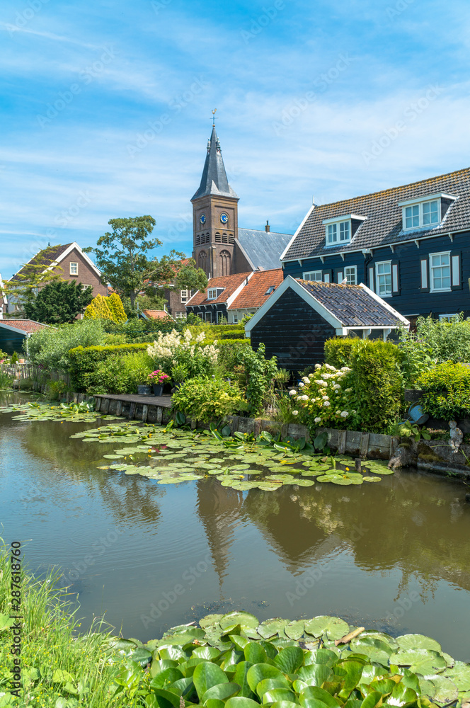 Marken, North Holland / Netherlands - June 23rd, 2019: Skyline of the old town with the church in the background and the canal in the foreground