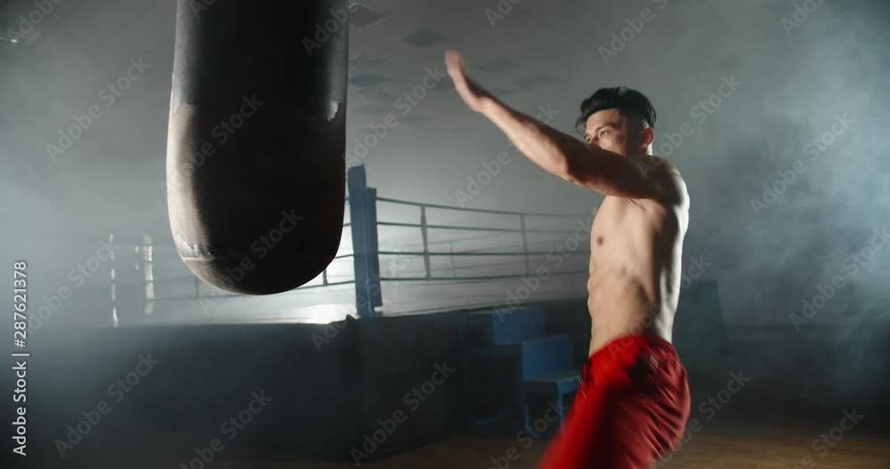 Asian man practicing muay thai highkick techniques on a punching bag, training before a fight - martial arts, sports concept 4k footage