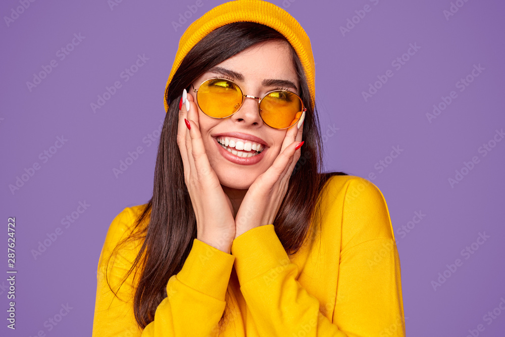 Surprised happy trendy woman in shades touching cheeks