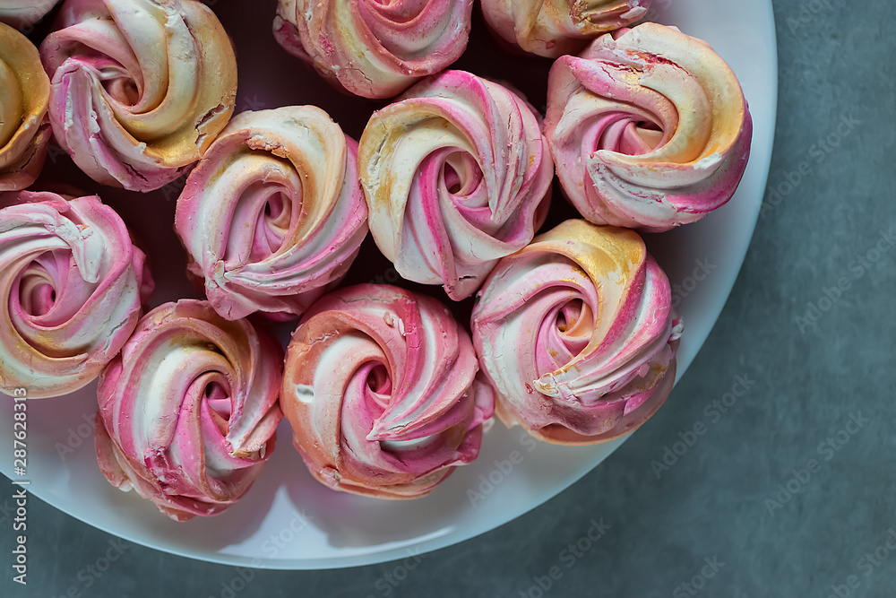 Beautiful bright multi-colored homemade marshmallow in the form of roses on a white plate. Top view. Beautiful bright multi-colored homemade marshmallow in the form of roses on a white plate. Top view.