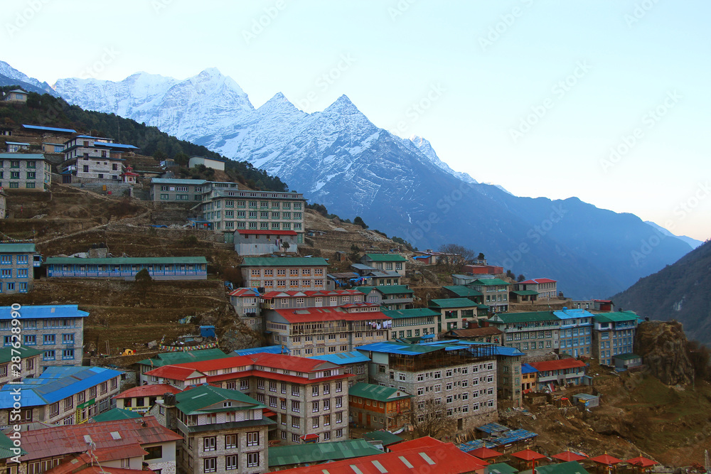 Cityscape of Namche Bazaar just before sunrise with Kangtega mountain in the background in Himalayas in Nepal. Outdoors, city view, bed and breakfast, mountains, hiking, travel and tourism concept.