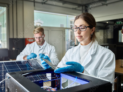 Two technicians working on solar cell in lab photo