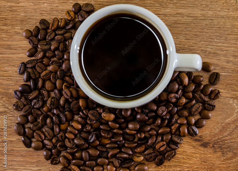 cup of coffee and a pile of coffee beans on a wooden background. Close-up.