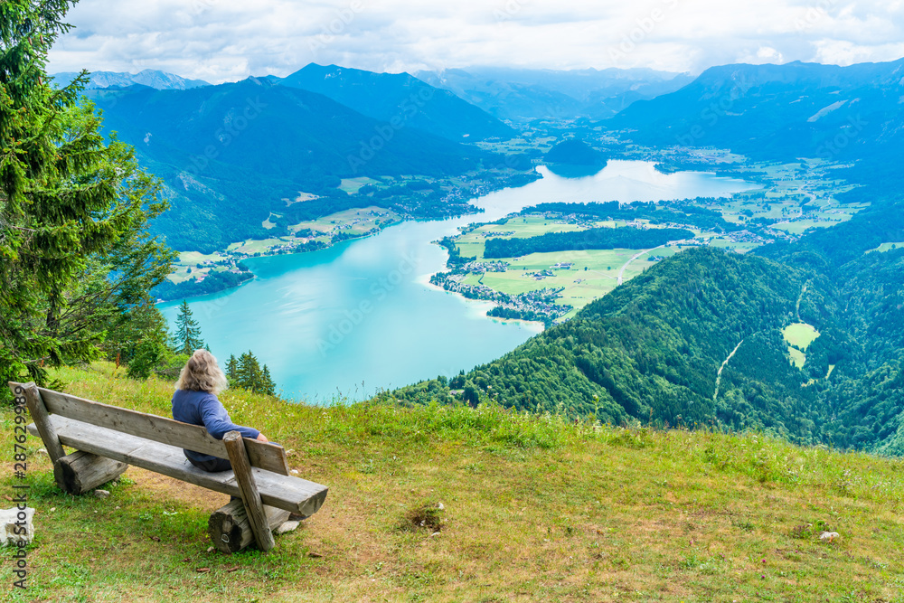 A male admires view of Wolfgangsee lake and surrounding mountains from Zwolferhorn mountain in St. Gilgen in Salzkammergut region, Austria