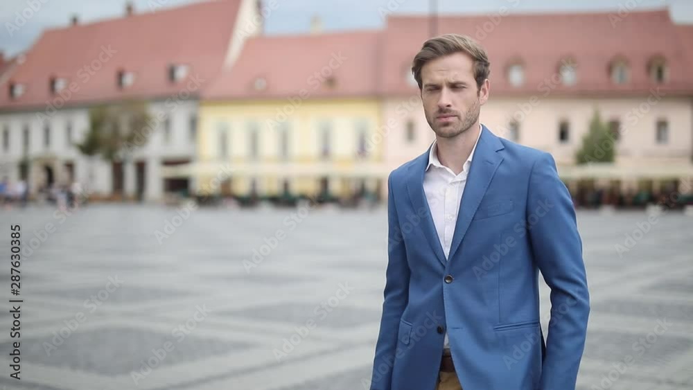 anxious smart casual man waiting for some one in the middle of a town square, looking from side to side 
