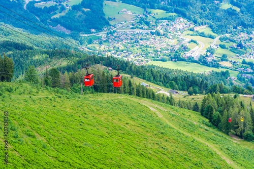 View of St.Gilgen village and colorful Seilbahn cable car gondolas against mountains in Salzkammergut region from Zwolferhorn mountain, Austria