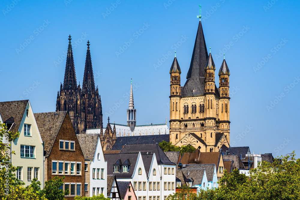 Skyline of the old town with solorful houses rooftops, the tower of the Cologne gothic cathedral and the tower of Gtreat St. Martin church in Cologne, North Rhine Westphalia, Germany