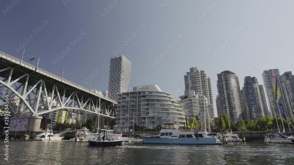Wide shot of false creek ferry passing under Granville bridge with Yaletown in background - sunny morning - Vancouver Canada Wide shot of false creek ferry passing under Granville bridge with Yaletown in background - sunny morning - Vancouver Canada