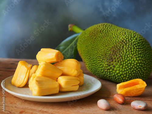 Ripe jackfruit flesh on white plate on wooden table for tropical fruit or meat substitute concept. photo