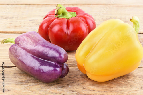 Multi-colored pods of sweet peppers on a wooden table. photo