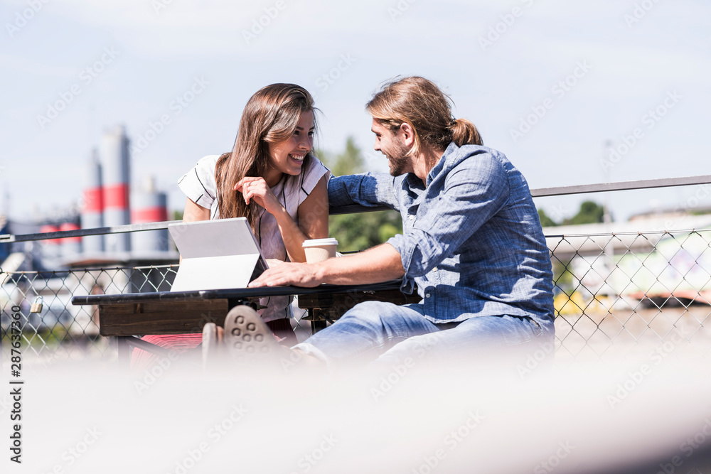 Happy young couple with tablet in a beer garden Happy young couple with tablet in a beer garden