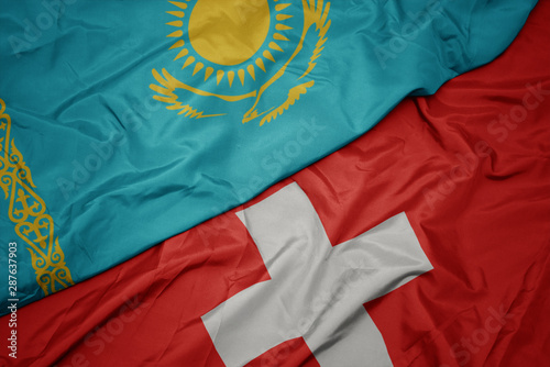 waving colorful flag of switzerland and national flag of kazakhstan.