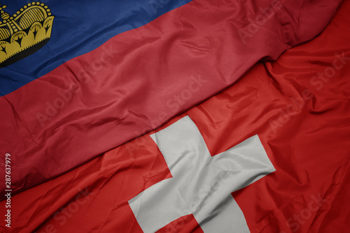 waving colorful flag of switzerland and national flag of liechtenstein.