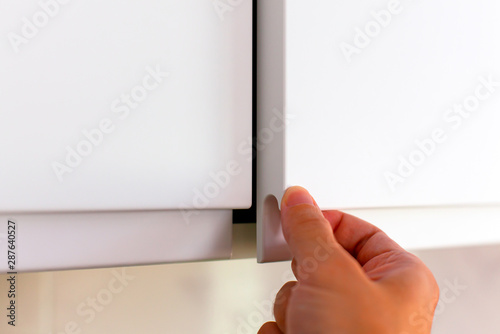 Person hand opening cupboard doors.