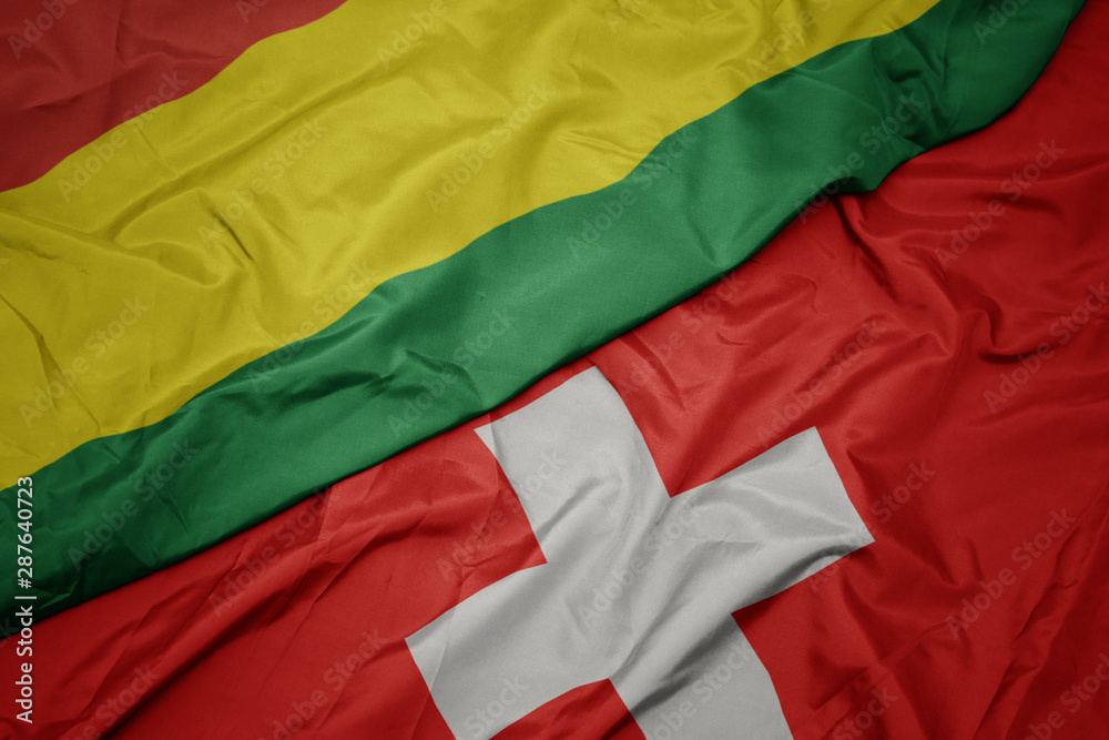 waving colorful flag of switzerland and national flag of bolivia.