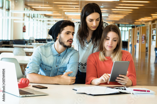 University students using digital tablet in university library.