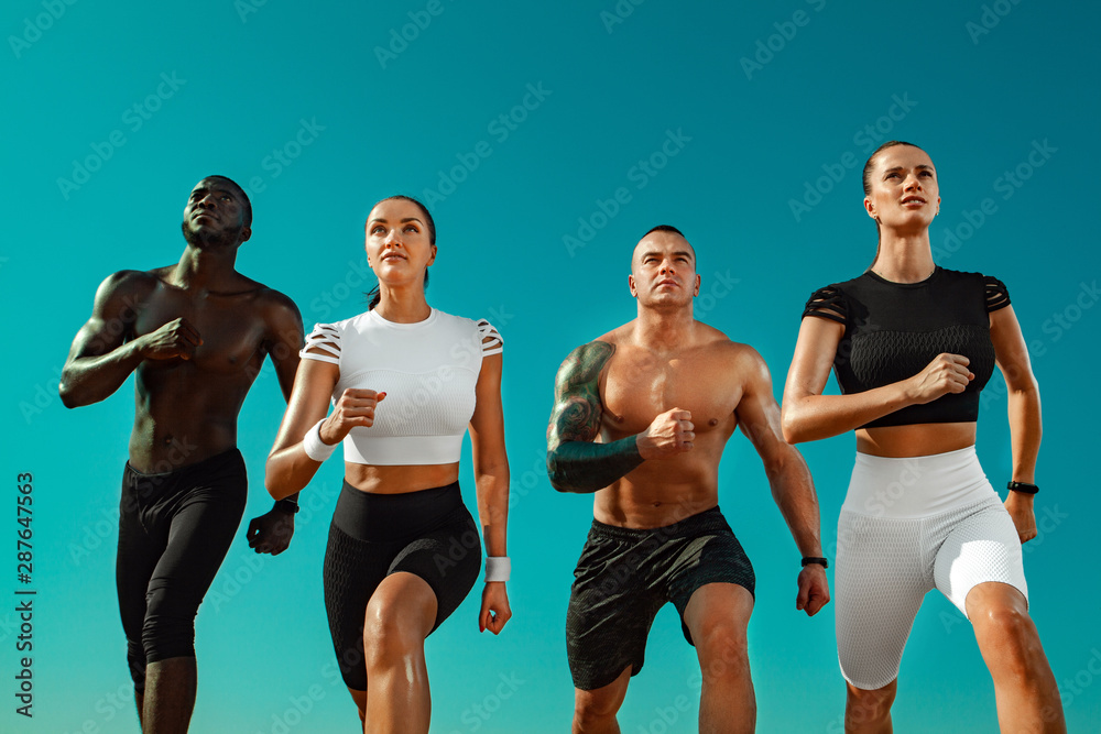 Group of young sportsmens women and men, fit athletes runners running on  the sky background. Healthy lifestyle and sport. Friends in black and white  sportswear on workout exercise. Fitness concept. ภาพถ่ายสต็อก