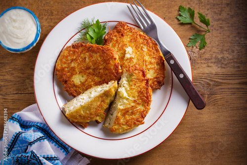 Potato Pancakes Stuffed With Cottage Cheese. Homemade vegetable fritters on white plate, wooden table