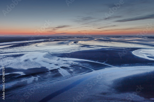 Aerial view of the ocean at low tide after sunset from Mont Saint Michel monastery. Textured abstract background. Normandy, France.