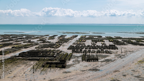 Cancale coast at low tide in a summer day, oyster farms in the foreground. Cancale is the oyster farming centre and seaside resort in Brittany, France.