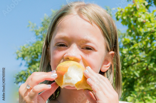 Little girl eating fresh pear photo