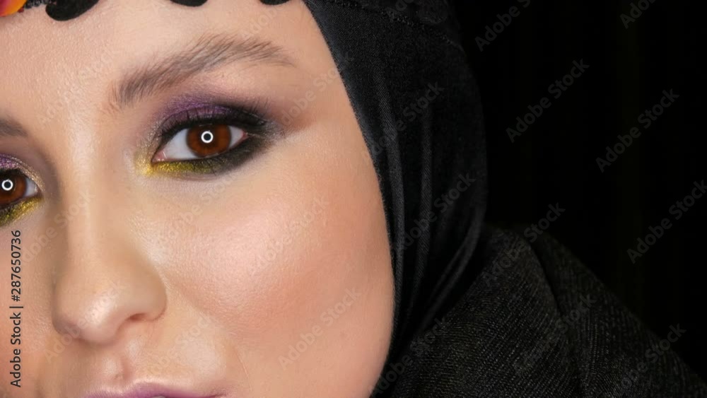 Professional girl model with beautiful makeup poses in a black cap and wreath on her head in front of the camera on a black background in the image of a black widow. High-fashion Professional girl model with beautiful makeup poses in a black cap and wreath on her head in front of the camera on a black background in the image of a black widow. High-fashion