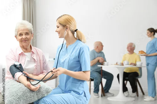 Obraz Pielęgniarka pomiaru ciśnienia krwi starszej kobiety w domu starców. Pomoc osobom starszym