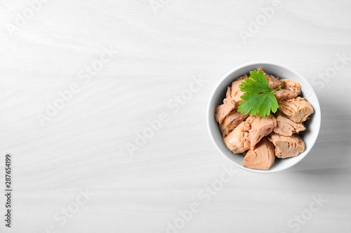 Bowl with canned tuna on light table, top view. Space for text photo