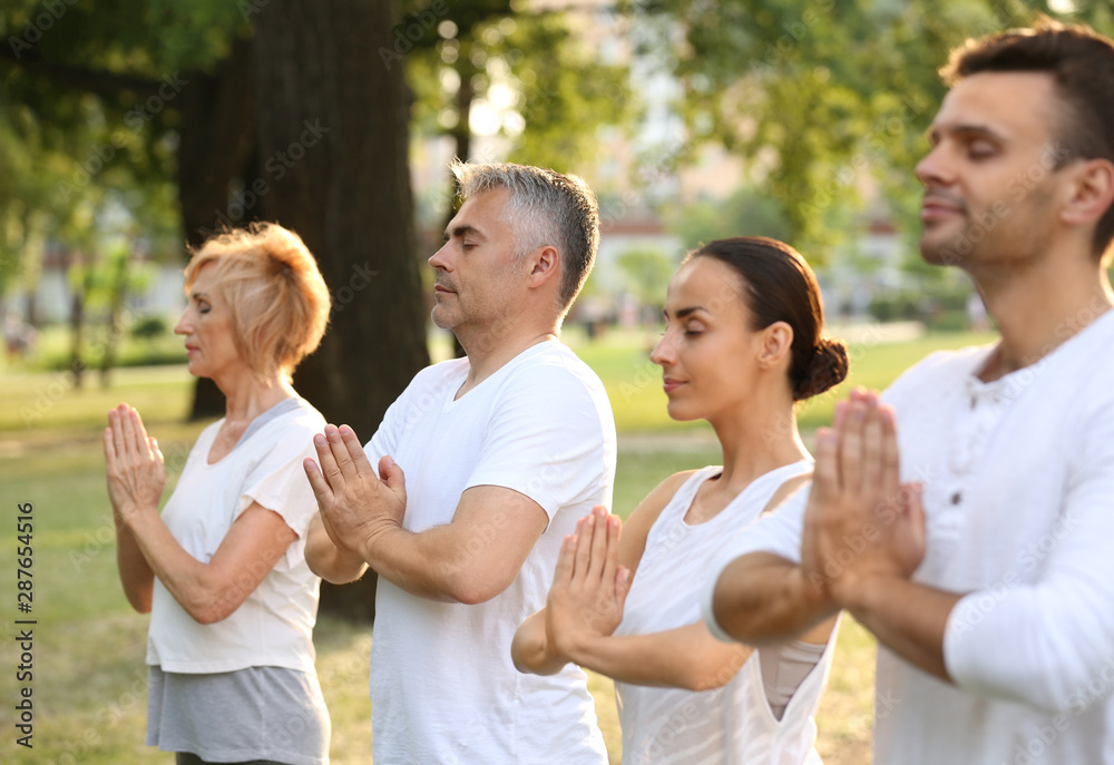 People practicing yoga in park at morning People practicing yoga in park at morning