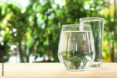 Glasses of water on table against blurred background, space for text. Refreshing drink