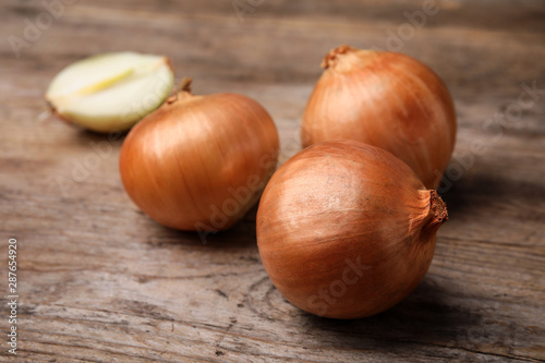 Ripe onions on rustic wooden table, closeup