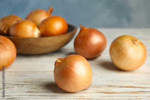 Ripe onions on white wooden table  closeup