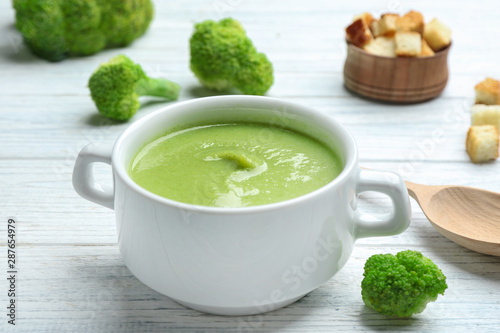 Bowl of broccoli cream soup served on white wooden table