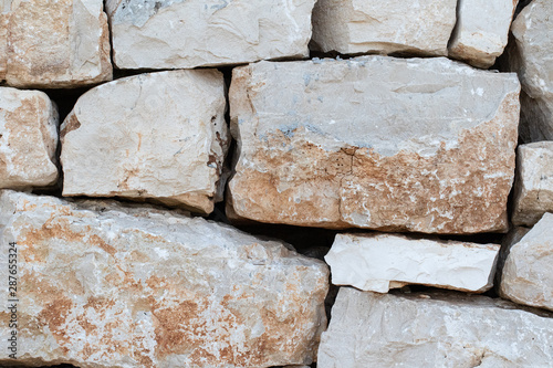 A closeup view of a drystone (drystack) wall filling the frame as a textured background with large boulders and natural sand stone colors, rustic and traditional walling. photo