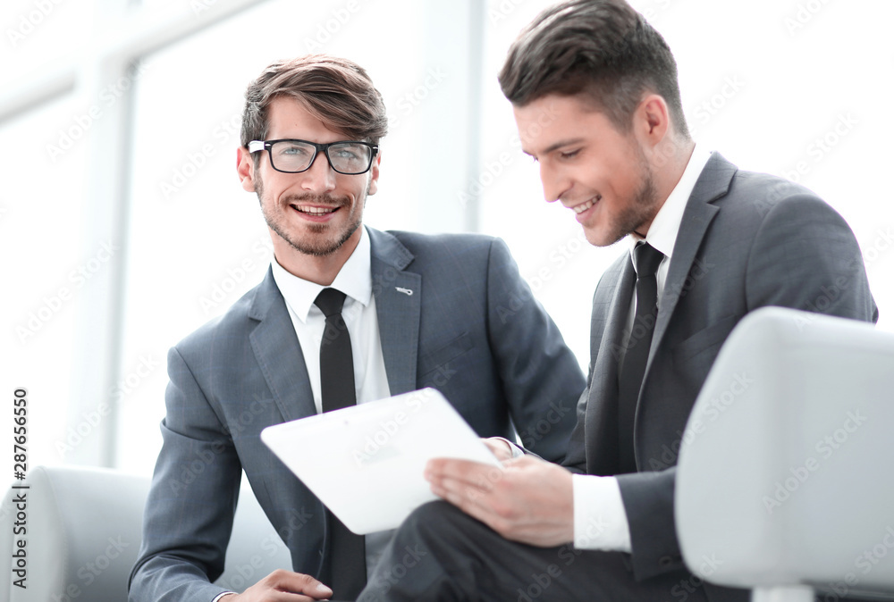 Two smiling elegant business people looking at something on digital tablet Two smiling elegant business people looking at something on digital tablet