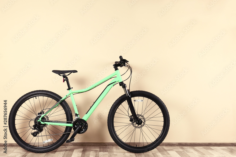 Fototapeta premium Modern bicycle near beige wall indoors. Healthy lifestyle