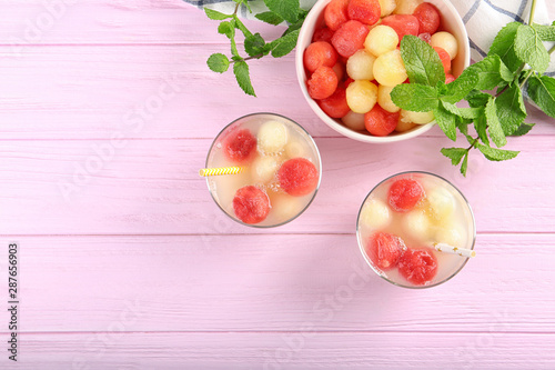 Glasses of melon and watermelon ball cocktail on pink wooden table, flat lay. Space for text