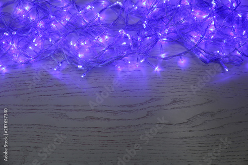 Blue Christmas lights on white wooden background, top view. Space for text