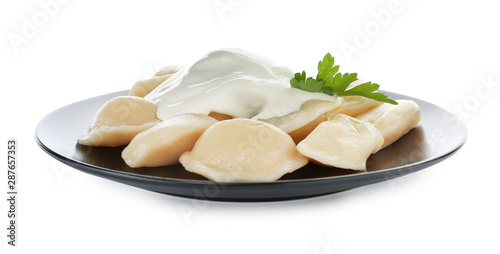 Delicious cooked dumplings with sour cream on white background
