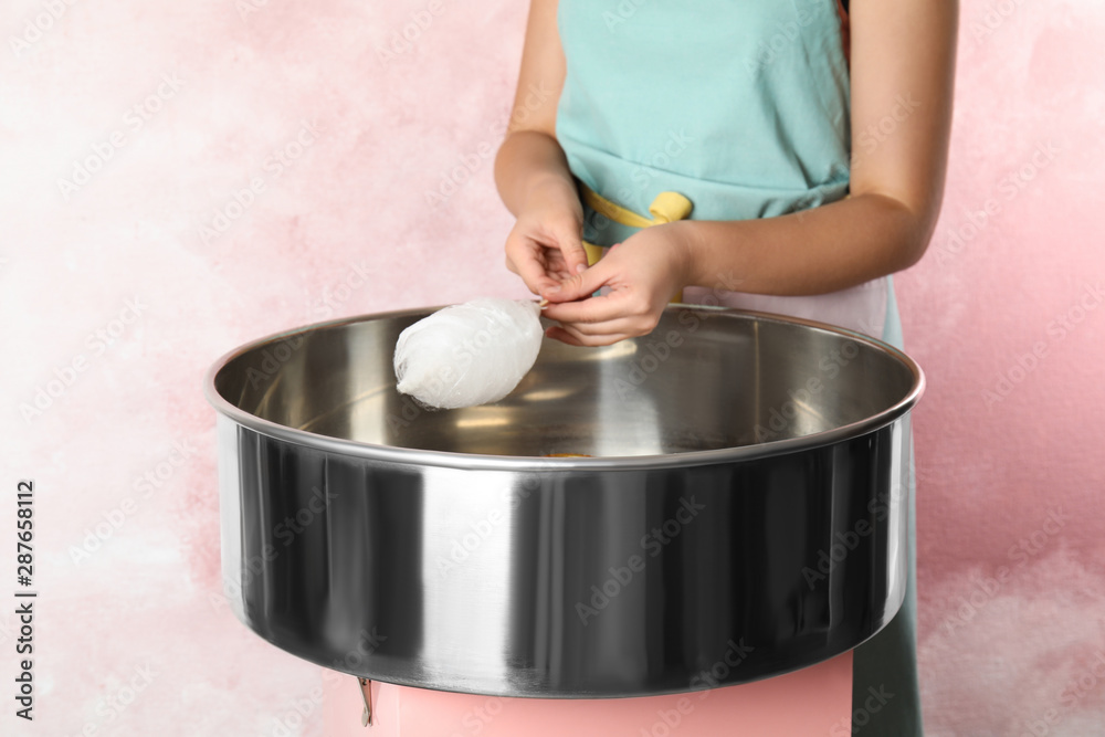 Young woman making cotton candy with modern machine on pink background, closeup Young woman making cotton candy with modern machine on pink background, closeup