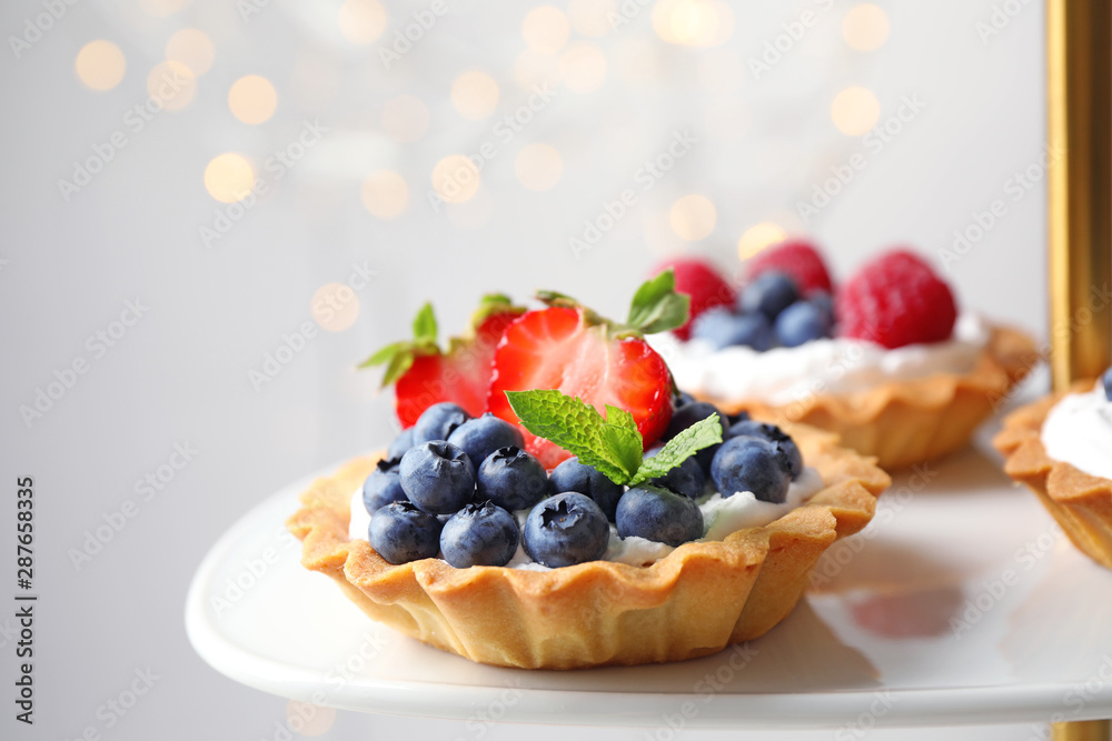 Tarts with different berries on cake stand. Delicious pastries